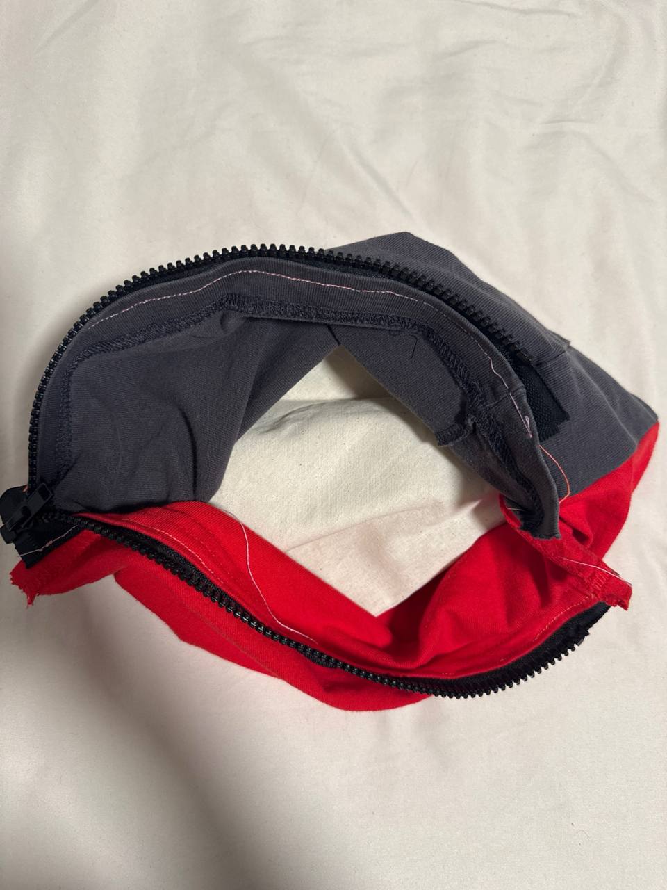 The t-shirt prototype 2 with the zipper fully open, showing the dark grey side and the red side meeting at the zipper and exposing the interior cavity of the sleeve