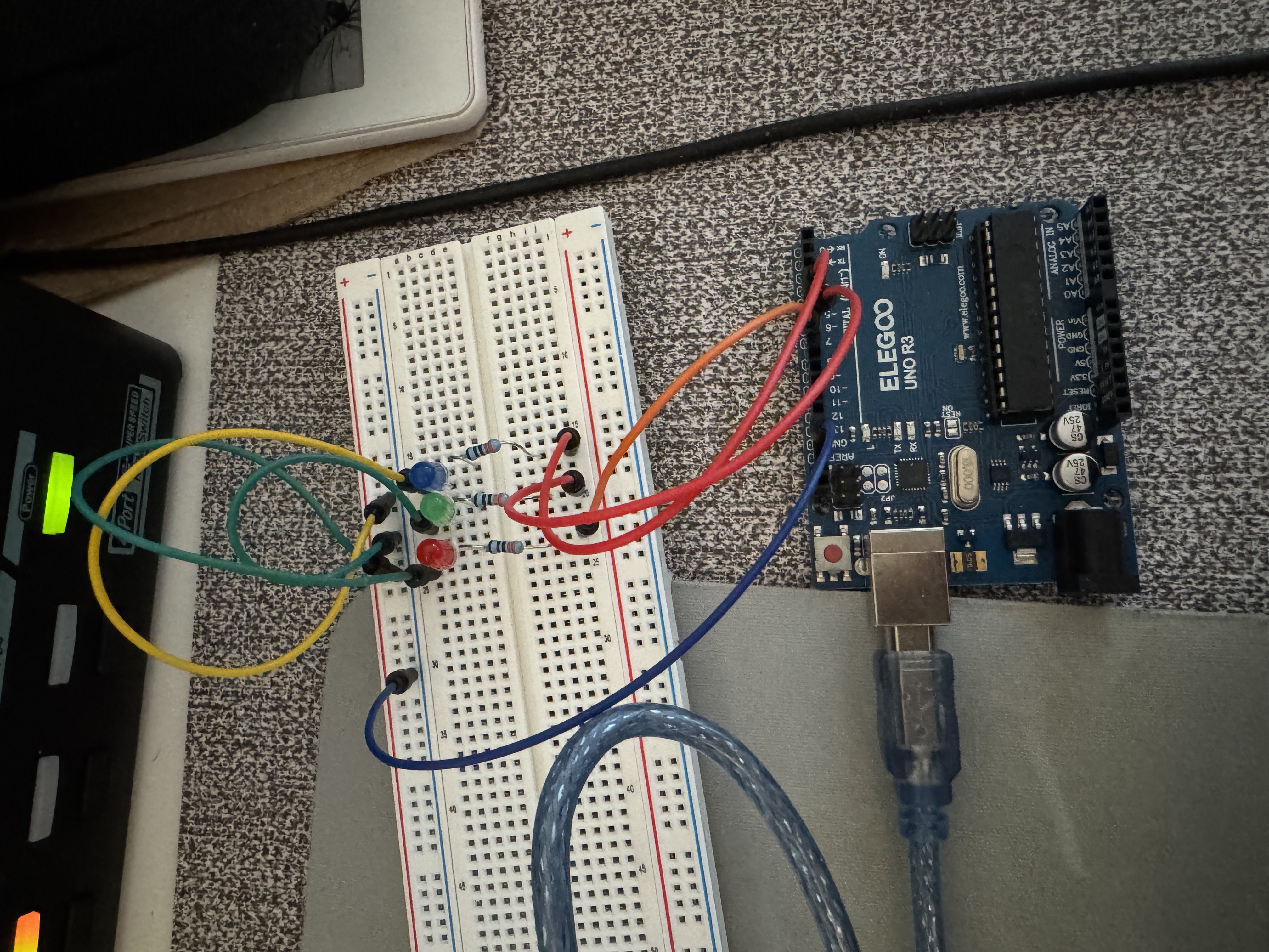 Actual ELEGOO UNO R3 breadboard circuit with separate red, green, and blue LEDs, three series resistors, jumper wires, and USB power.